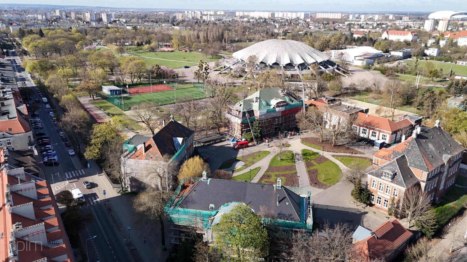 Cztery zabytkowe budynki na Łazarzu zyskują nowe dachy Zdjęcie przedstawia cztery zabytkowe budynki na Łazarzu oraz Arenę z lotu ptaka.