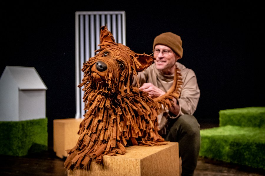 Złocistobrązowa, klasyczna lalka pieska wraz z aktorem na scenie.