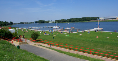 ludzie opalający się na plaży i kąpiący się w wodzie