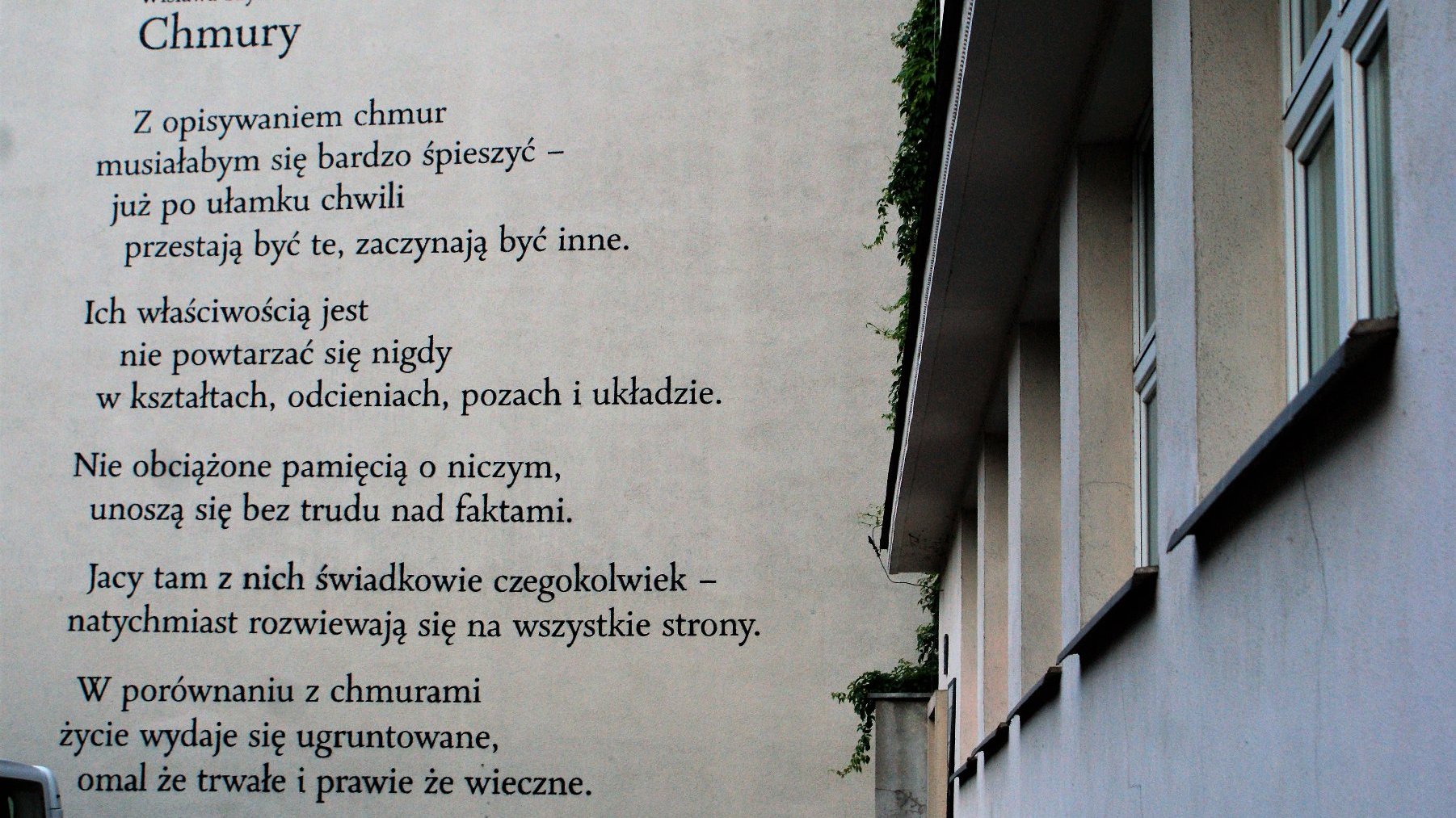 Dwie kamienice. Na ścianie kamienicy wiersz.