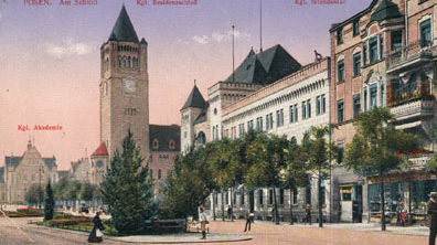 Ulica św. Marcin z widokiem na wieżę zegarowa Zamku Cesarskeigo. Na ulicy ludzie, klomby roślinne i alejka drzew wzdłuż kamienic po prawej stronie.