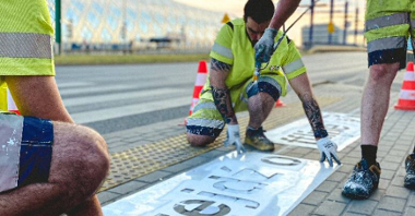 Men creating a sign "Go Offline" near a walkway.