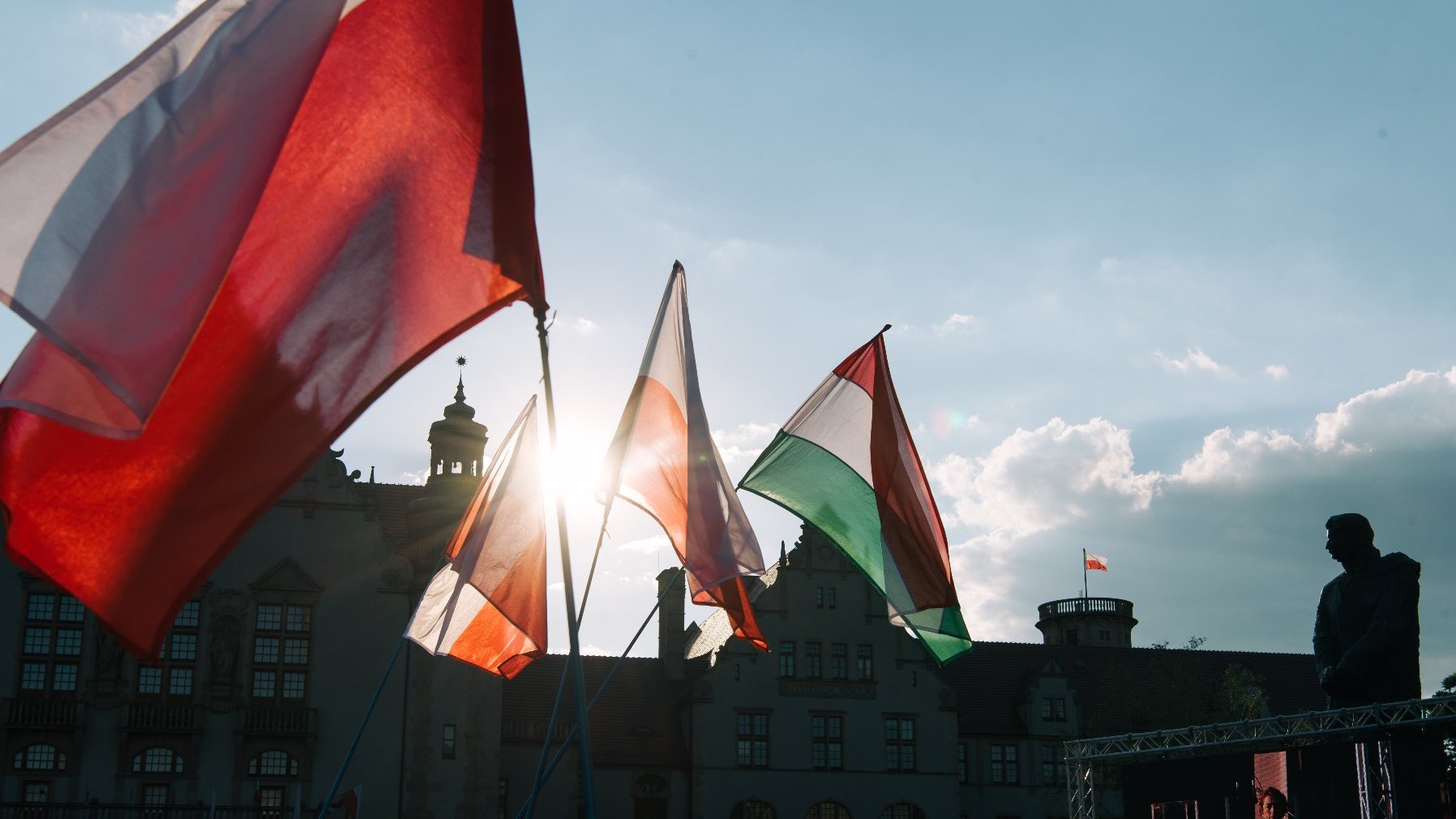 Four flags, in the background building and sunset.