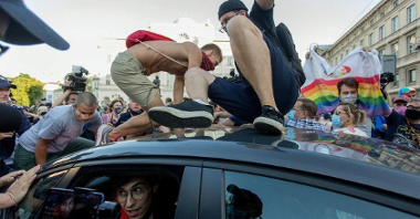 Photo from the movie: two young men on a car roof. Behind a car a crowd of people - it looks like a demonstration.
