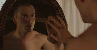 Photo from the movie: a young undressed man looking at the mirror on his reflection and touching the mirror with his right hand