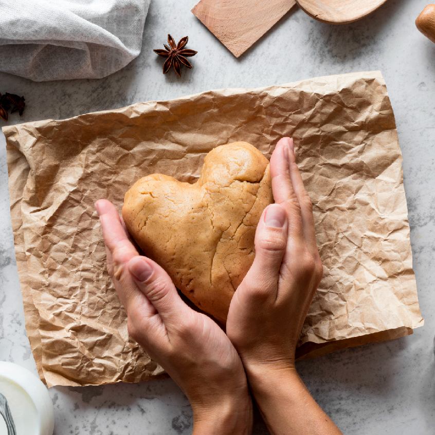 Gingerbread dough held in hands folded into a heart shape - grafika artykułu