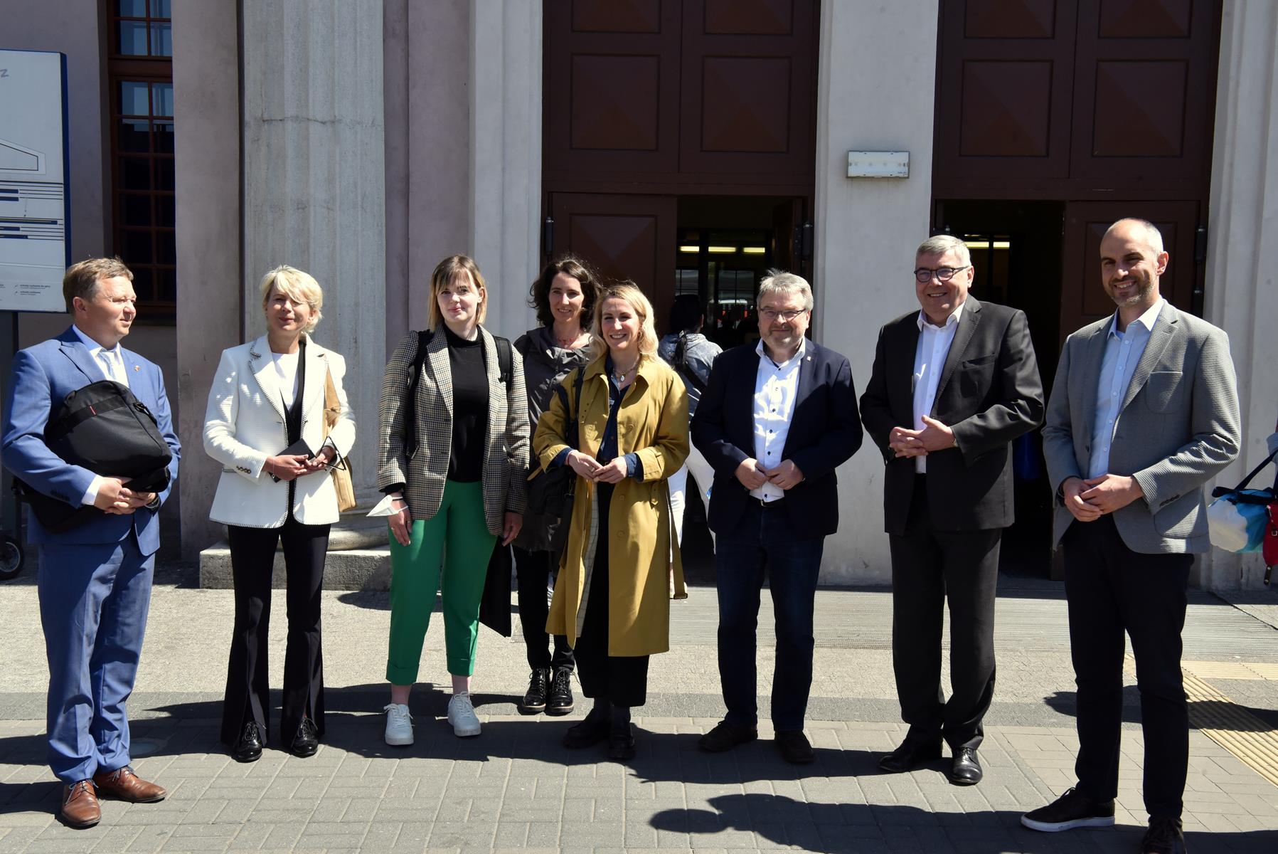 The photo shows the delegation - a group of people standing side by side, with the train station building behind them - grafika artykułu