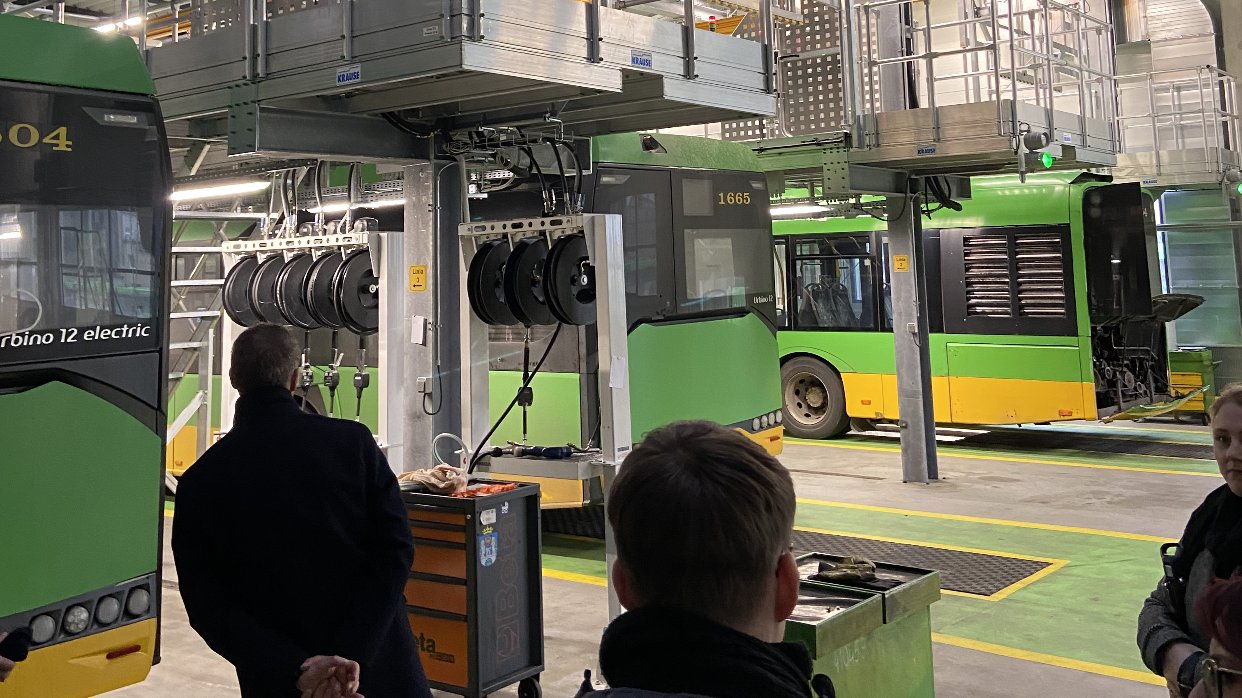 The photo shows several people in the background of the buses