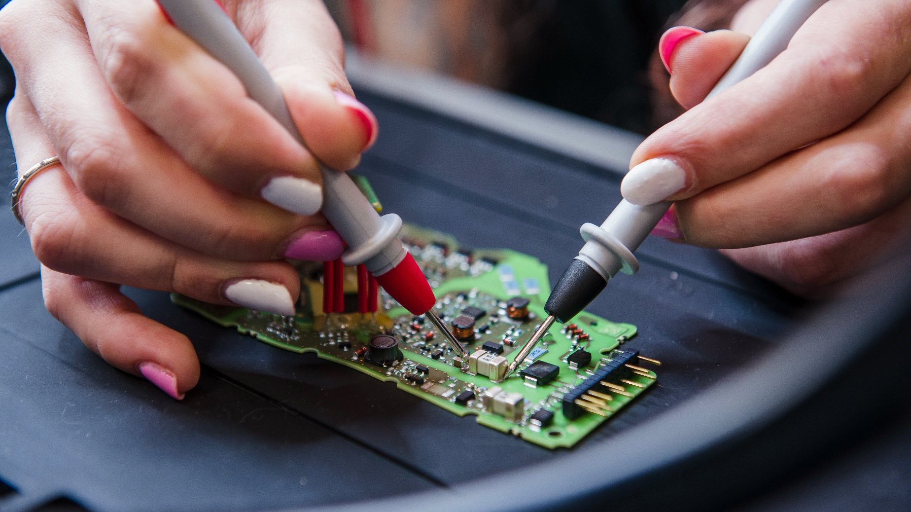 Two hands work on an electrical component.