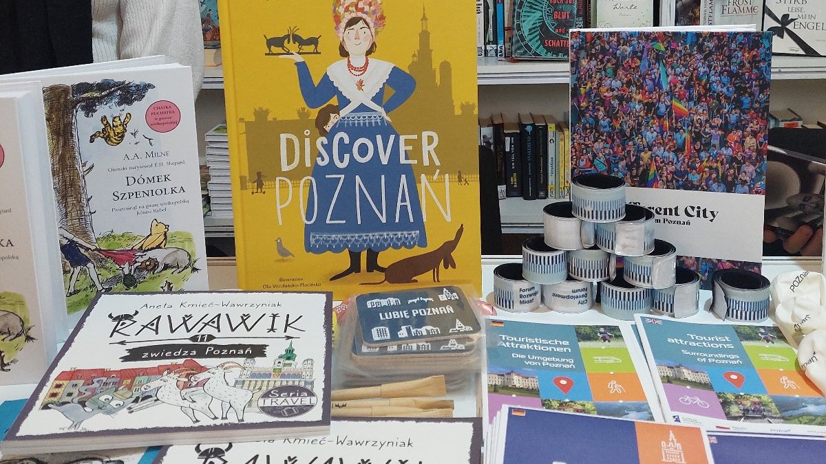 In the photo, there are numerous books displayed behind a counter. They are spread out before the viewer's eyes.