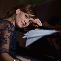 Alina Kubiak z głową opartą o fortepian.