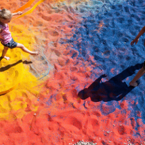 Dzieci chodzące po kolorowym, barwionym kruszywie.