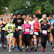 Grupa biegnących osób w biegu konstytucyjnym. Każdy zawodnik ma naklejony numer startowy.