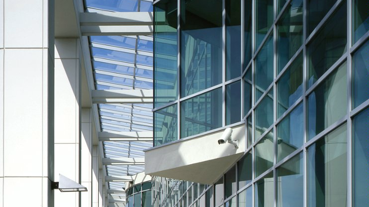 Zdjęcie przedstawia kolumnadę, za którą znajdują się okna Centrum Wykładowego Politechniki Poznańskiej. Część przeszkleń "wystaje" z elewacji w formie wykuszy.