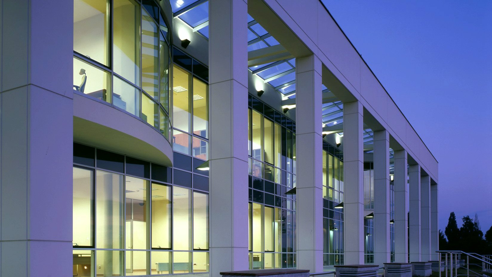 Zdjęcie przedstawia kolumnadę, za którą znajdują się okna Centrum Wykładowego Politechniki Poznańskiej.