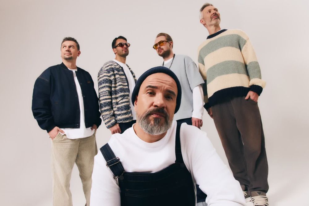 Czterech mężczyzn stoi, jeden kuca.