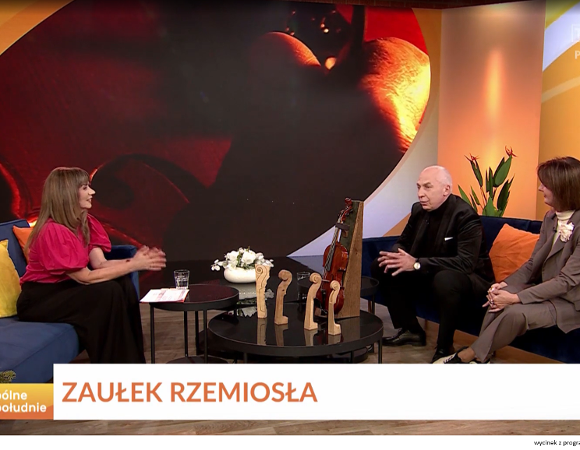 Dwoje ludzi siedzi na kanapie w studiu telewizyjnym i udziela wywiadu
