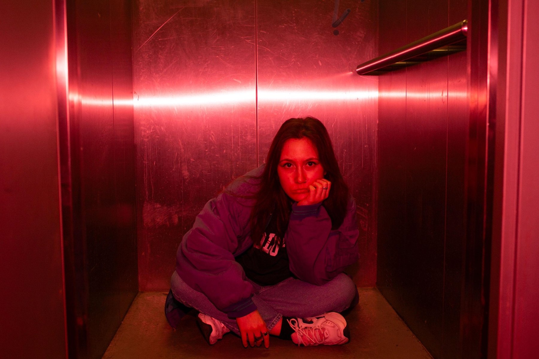 Dziewczyna siedzi na podłodze w windzie lub w szafie