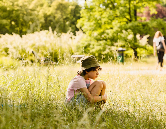 dziewczynka siedząca samotnie na trawie w parku