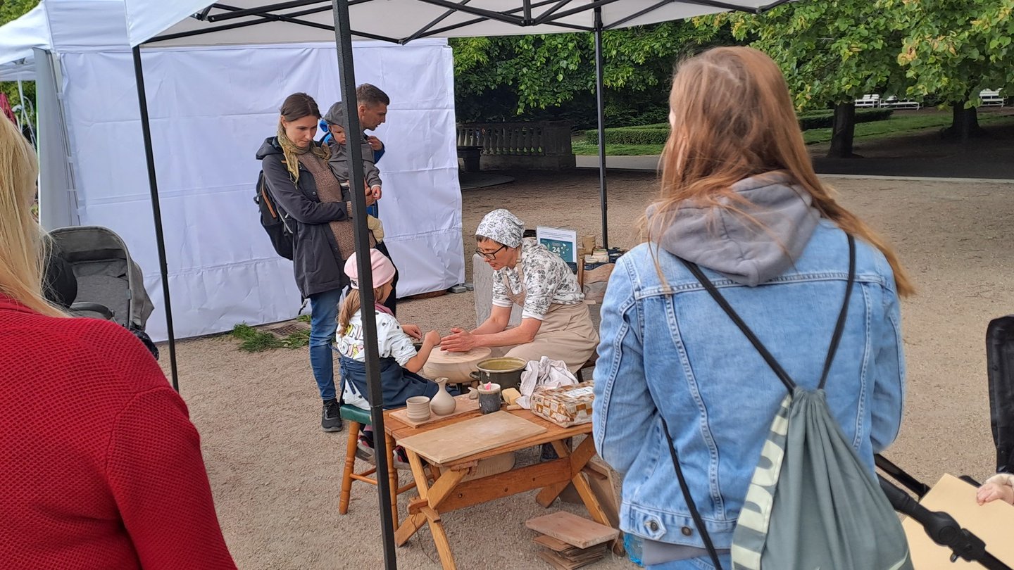 Chętni oglądają pokaz toczenia naczyń ceramicznych na kole.