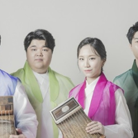 Kolorowa fotografia ukazuje cztery osoby pochodzenia koreańskiego, stojące na wprost aparatu. Trzech mężczyzn oraz kobieta ubrani są w tradycyjne koreańskie stroje. Dwoje muzyków trzyma w dłoniach instrumenty którymi są cytry. Składają się z płaskiego pudła oraz strun.