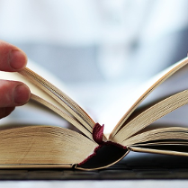 Dłonie trzymają otwartą książkę.