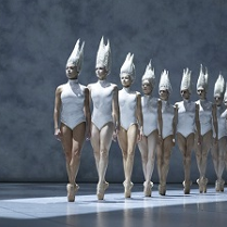 na zdjęciu po lewej stronie chłopiec patrzący przez duże okno, przed oknem rząd baletnic w białych strojach typu body i białych nakryciach głowy