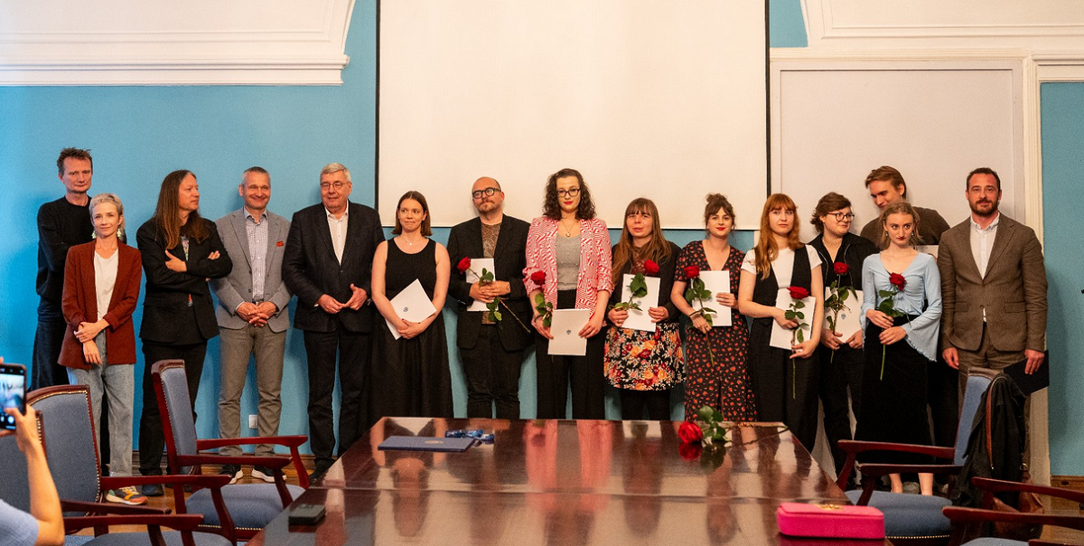 Laureatka i laureaci stypendiów artystycznych Miasta Poznania, przedsawiciele kapituły oraz samorządu Miasta Poznania grupa około kilkunastu osób kobiet i mężczyzn w różnym wieku pozuje do wspólnego zdjęcia, znajdują się w pomieszczeniu