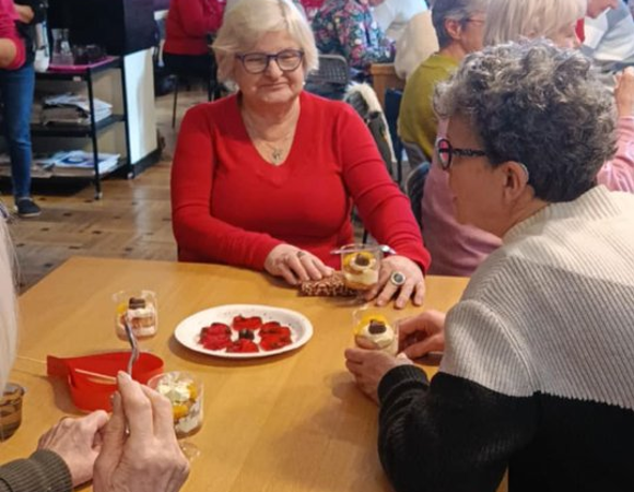 Kobiety rozmawiają przy stole jedząc deser.