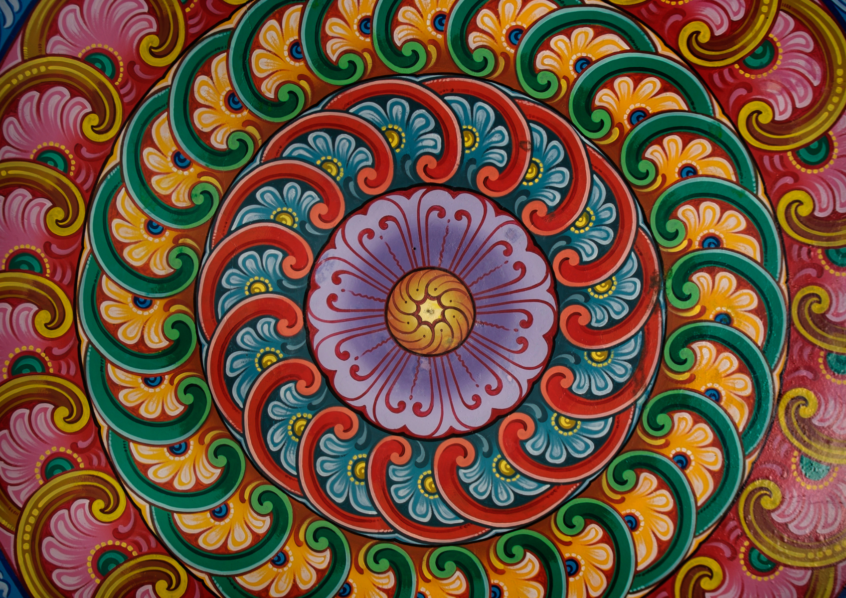 Kolorowa mandala namalowana farbami, kolory: czerwony, zielony, żółty, różowy i fioletowy, wzór kwiatowy