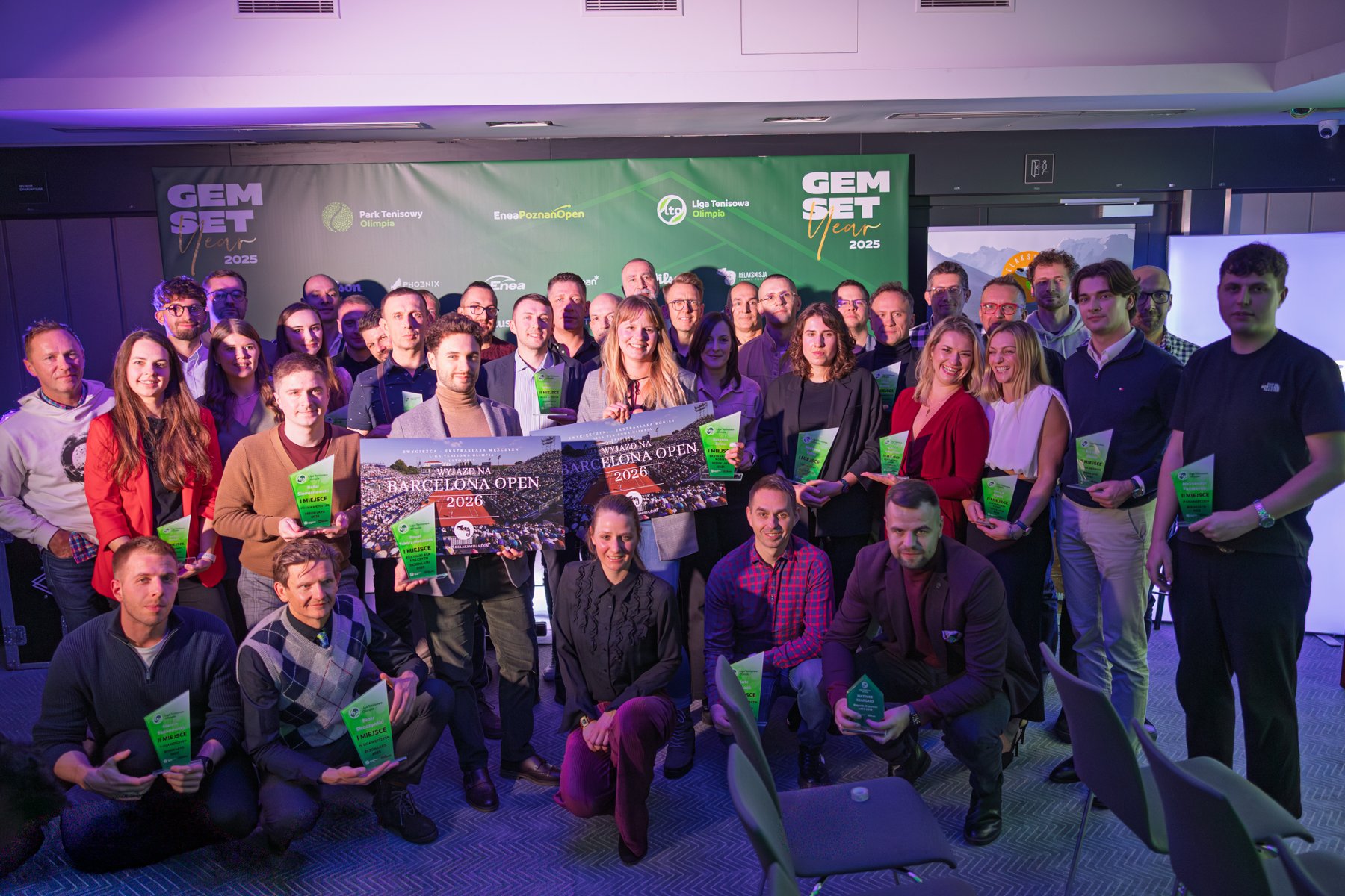 Laureaci letniej edycji Ligi Tenisowej Olimpia 2025, fot. Klaudia Berda - na tle ścianki stoi kilkadziesiąt osób, które trzymają statuetki