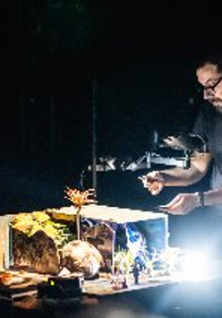 Mężczyzna pochyla się nad oświetloną makietą.