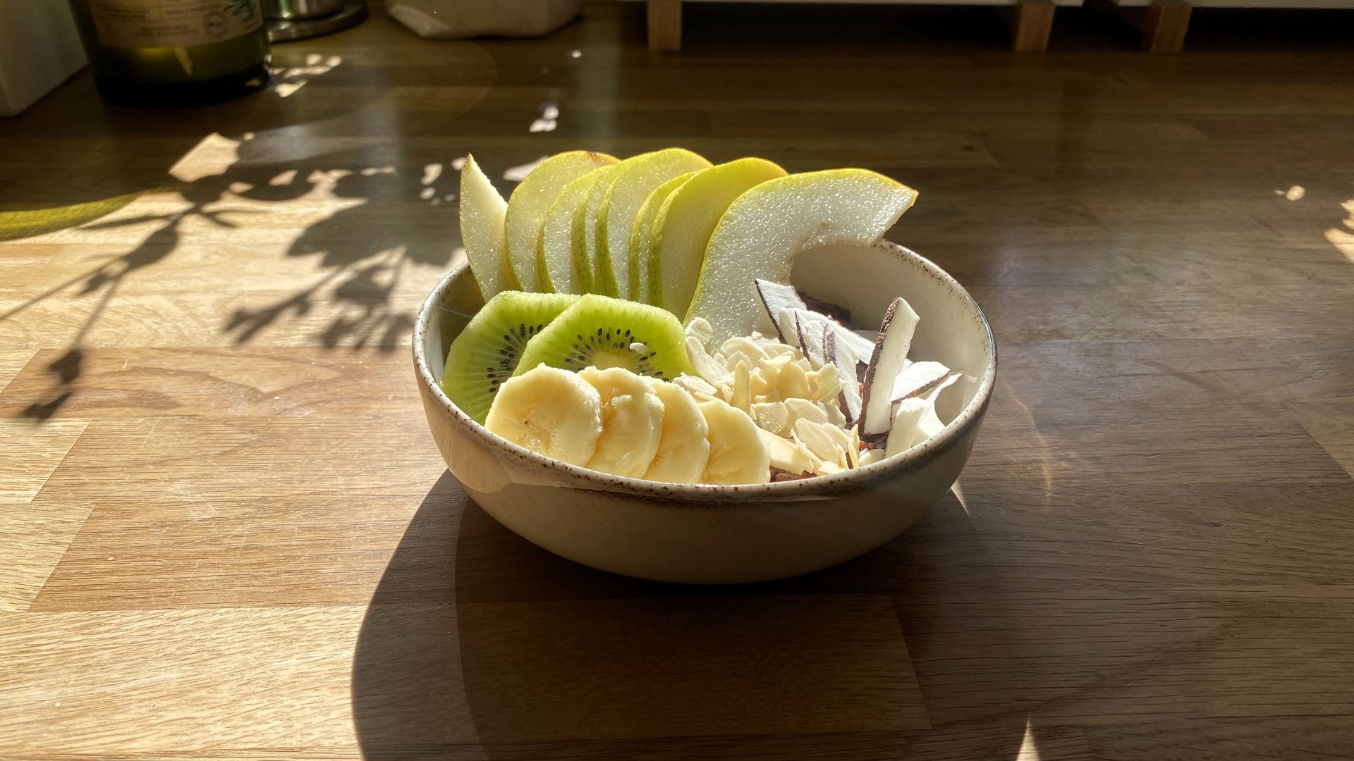 Gryczanka z dodatkiem ulubionych owoców oraz płatków migdałowych i kokosowych, fot. AL Miseczka z czkoladową gryczanką, kawałkami gruszki, kiwi i banana oraz płatkami migdałów i kokosa.