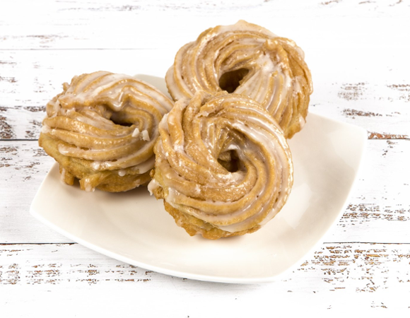 Na białym talerzu trzy ciastka - gniazdka poznańskie.