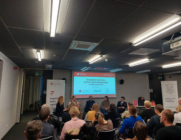 Na fotografii widoczna jest kobieta oraz osoby słuchające wykładu