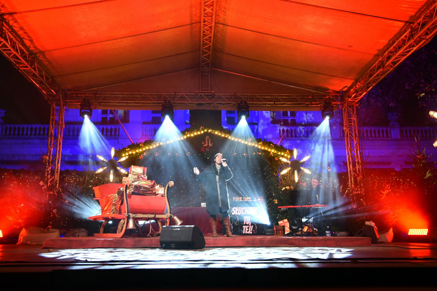 na scenie stoi kobieta z mikrofonem i śpiewa kolędę