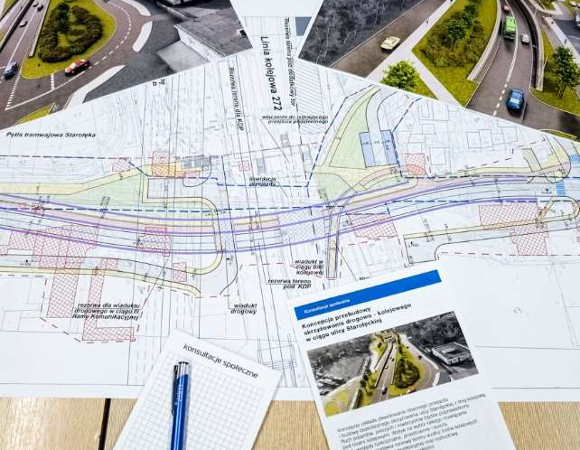 zdjęcia z dyżuru konsultacyjnego przeprowadzonego w ramach konsultacji społecznych Na stole leży mapa z koncepcją drogową, wizualizacje, ulotka konsultacyjna i długopis