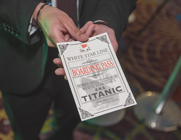 Na zdjeciu dłonie mężczyzny podającego kartę pokładową, będącą biletem na wystawę pod tytułem "Titanic: The Artifact Exhibition".