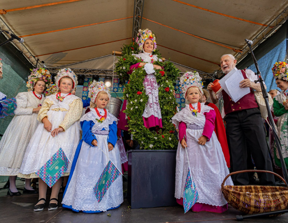Na zdjęciu kilka osób w strojach Bambrów, w centrum kobieta z wiadrami wody i wieńcem na szyi