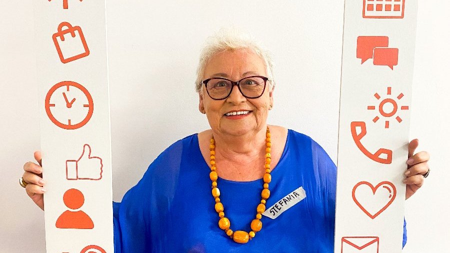 Na zdjęciu kobieta trzymająca ramkę z napisem: poznańska akademia wolontariatu senioralnego