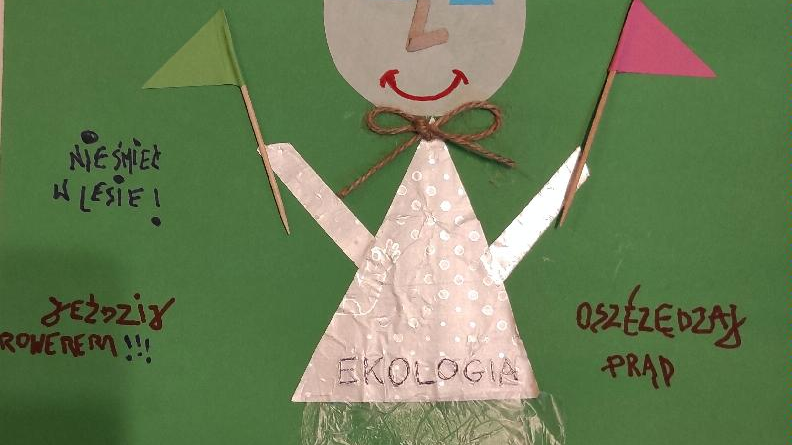 zdjęcie przedstawia plakat zatytuowany "Dbaj o środowisko!". Plakat przedstawia człekokształtną postać - Ekologię - która trzyma dwie chorągiewki, a woków niej widnieją ekologiczne hasła