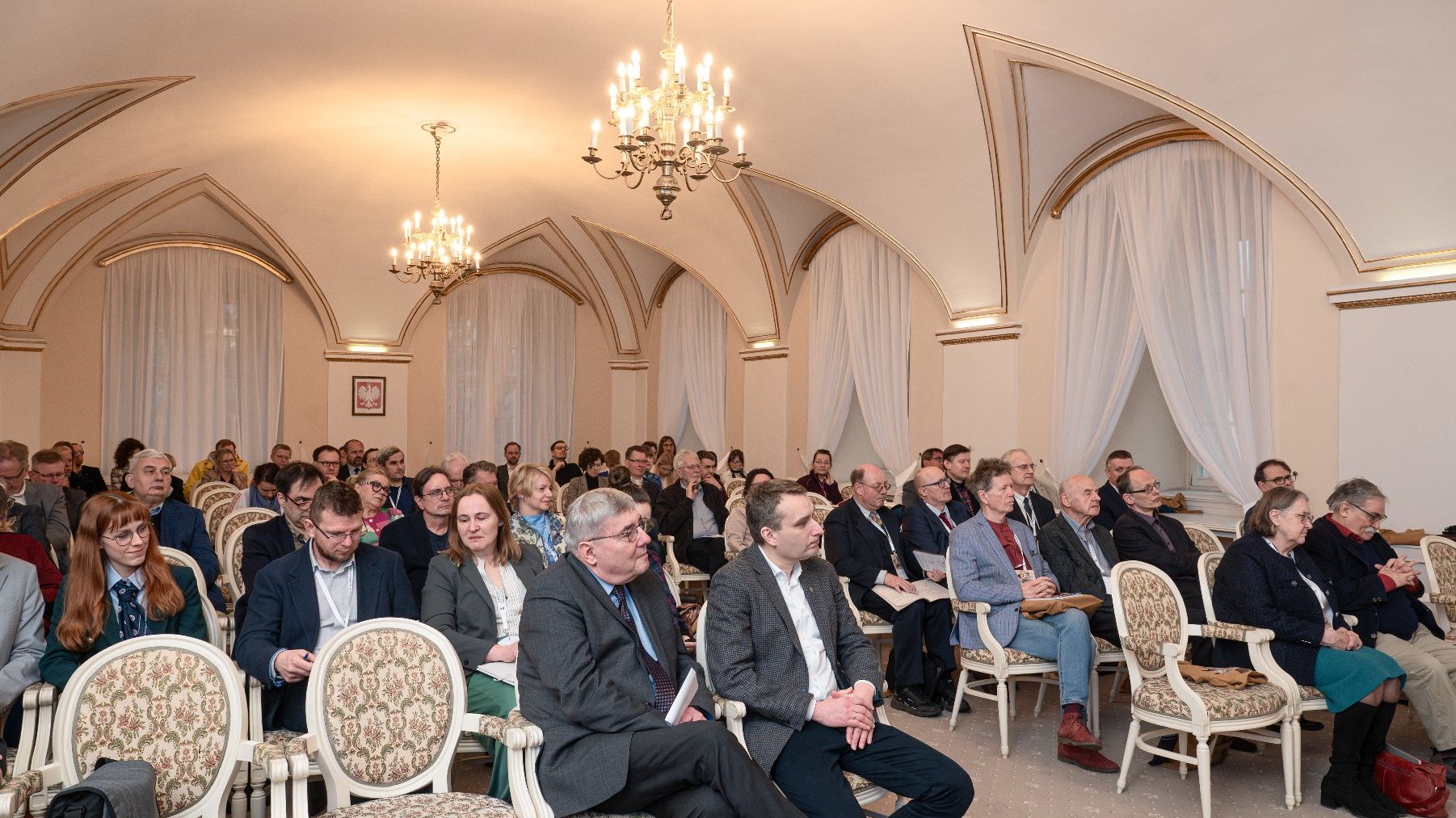 Zdjęcie przedstawia tłum ludzi siedzących na sali.