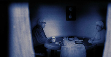 Melancholijny, ciemny obrazek. Starsze małżeństwo siedzi przy stole, na którym stoi ciasto i filiżanka oraz szklanka herbaty. Spoglądają na siebie.