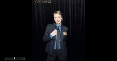 Młoda blondynka o jasnych oczach i cerze, ubrana w ciemny garnitur i niebieską koszulę z czarnym krawatem. Na zdjęciu napis "Oscars95".