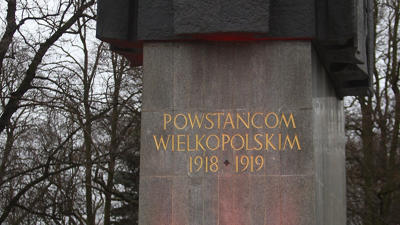 Zdjęcie pomnika Powstańców Wielkopolskich. Przed pomnikiem palący się znicz, obok pomnika żołnierze.