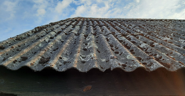 Galeria zdjęć przedstawia stodołę, której dach wykonany jest z szarych dachówek, zawierających azbest.