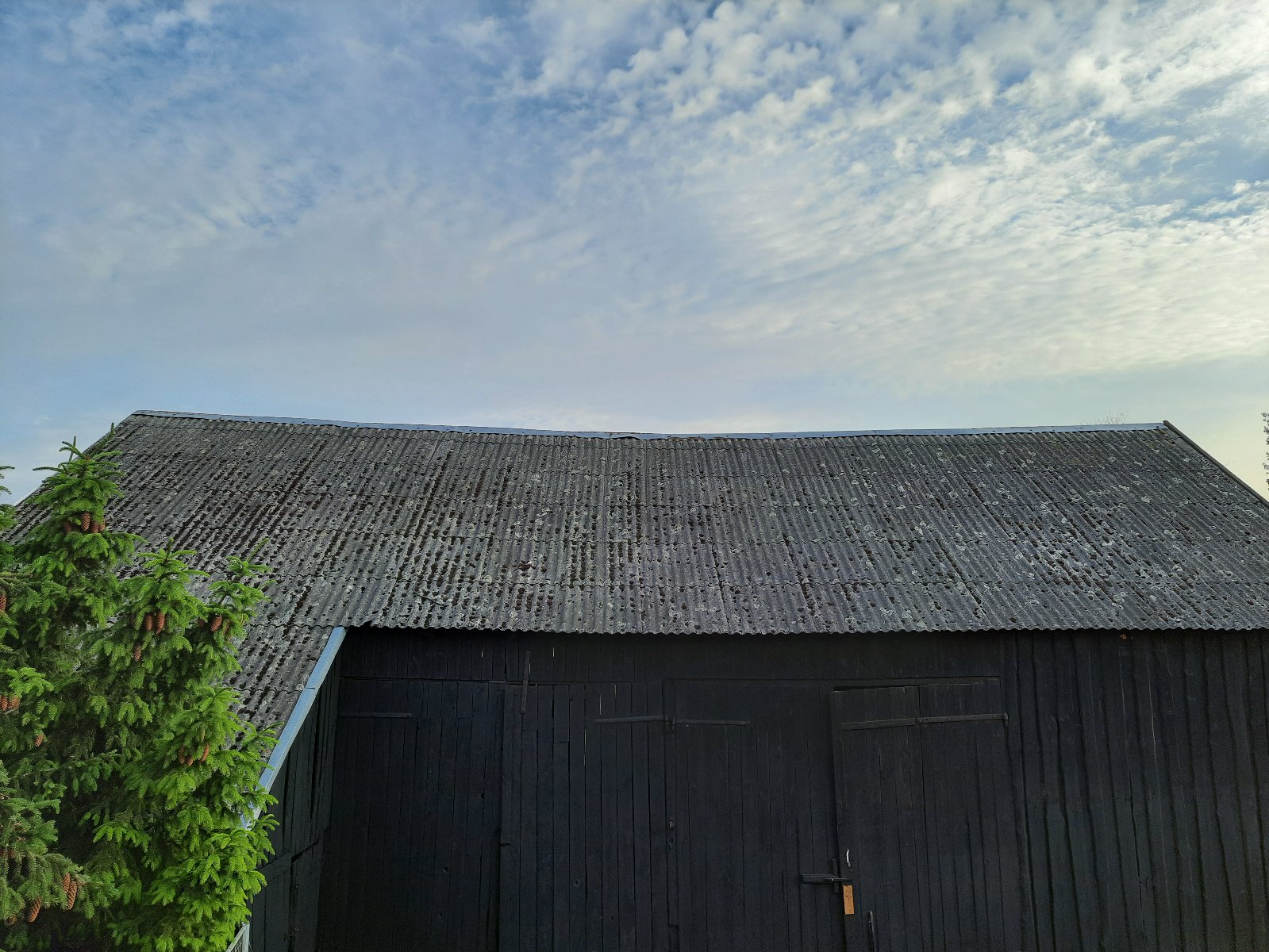 Galeria zdjęć przedstawia stodołę, której dach wykonany jest z szarych dachówek, zawierających azbest. - grafika artykułu