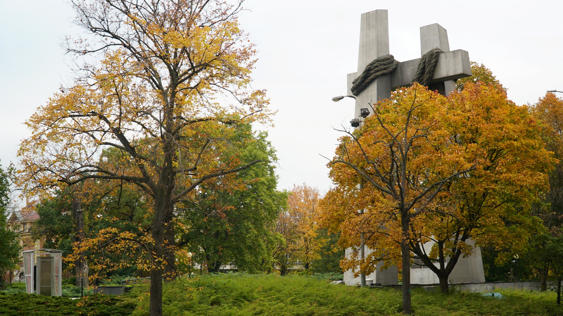 Zdjęcie przedstawia plac, którego elementem głównym jest pomnik Ofiar Czerwca 56 w postaci dwóch złączonych krzyżów. Wokół dużo drzew. - grafika artykułu