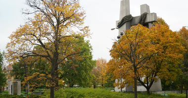 Zdjęcie przedstawia plac, którego elementem głównym jest pomnik Ofiar Czerwca 56 w postaci dwóch złączonych krzyżów. Wokół dużo drzew.