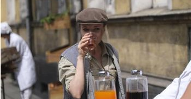 Kobieta w stroju z lat 50 pijąca napój przy saturatorze.